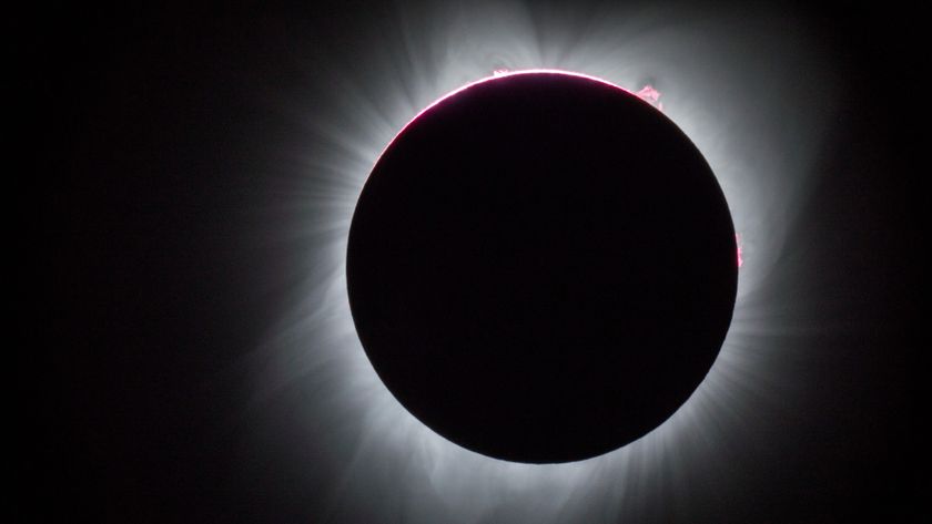 A photograph of a fully eclipsed sun, with white spikes of coronal energy shooting out from behind the moon