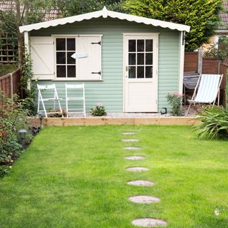 house in garden with blue wall and white chairs
