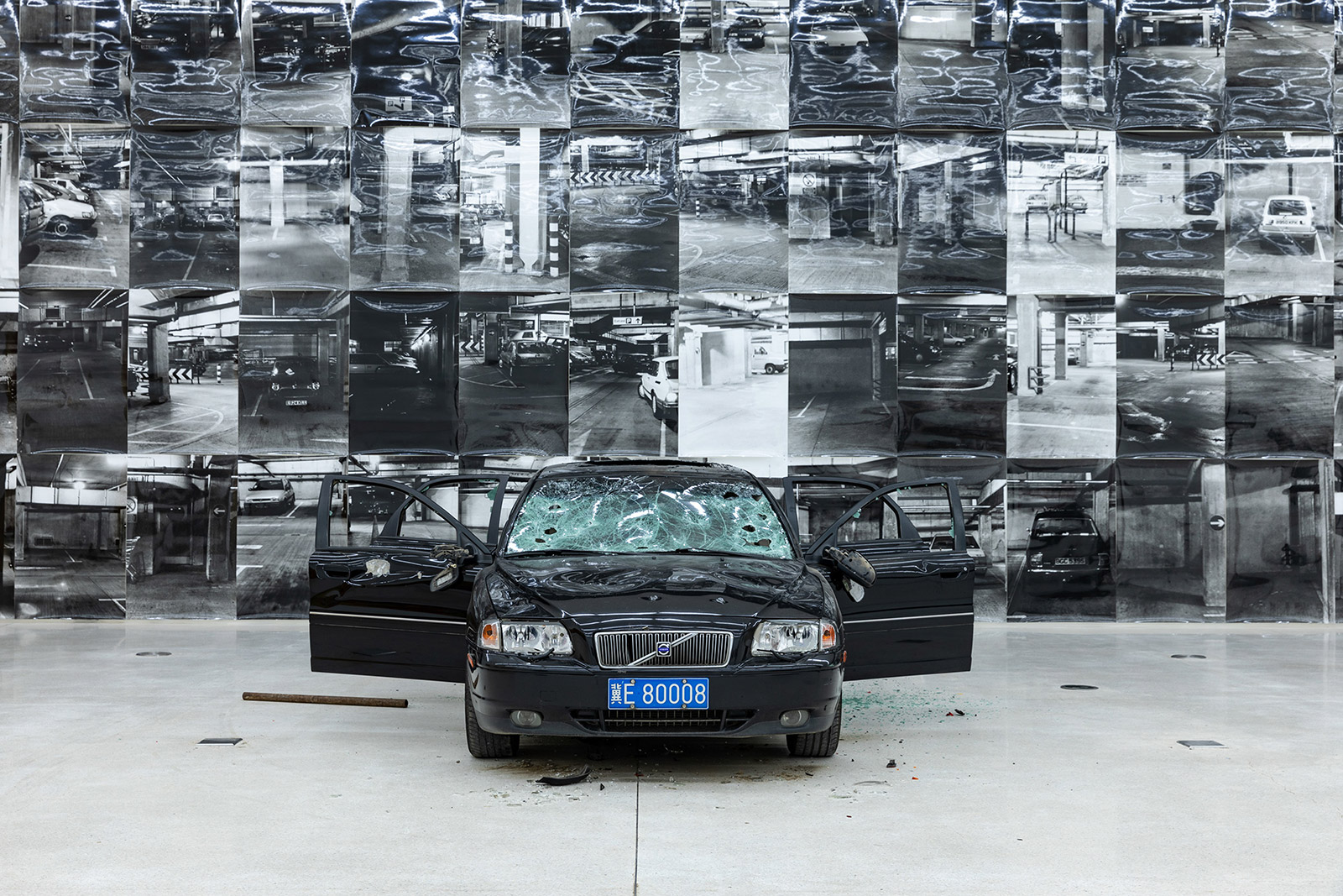 Damaged car with smashed glass and CCTV images on wall