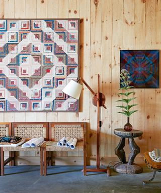 mudroom with pine cladding, wood and rattan chairs, wooden floorlamp and antique patchwork quilt