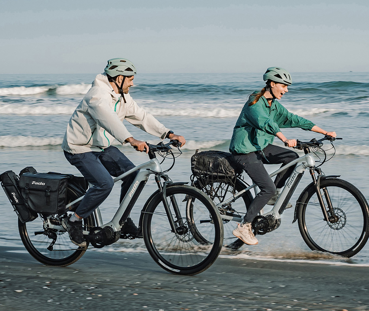 Two people riding Fiido Nomads Pros on the beach
