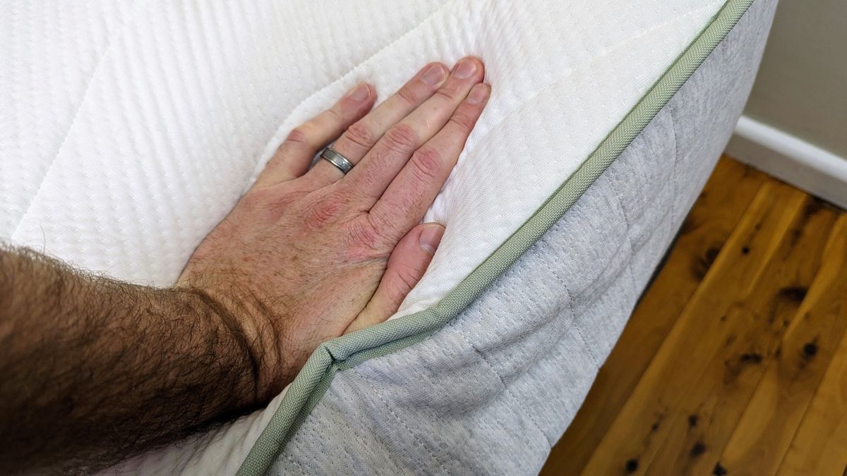 Koala SE mattress side with hand pressing down showing edge support