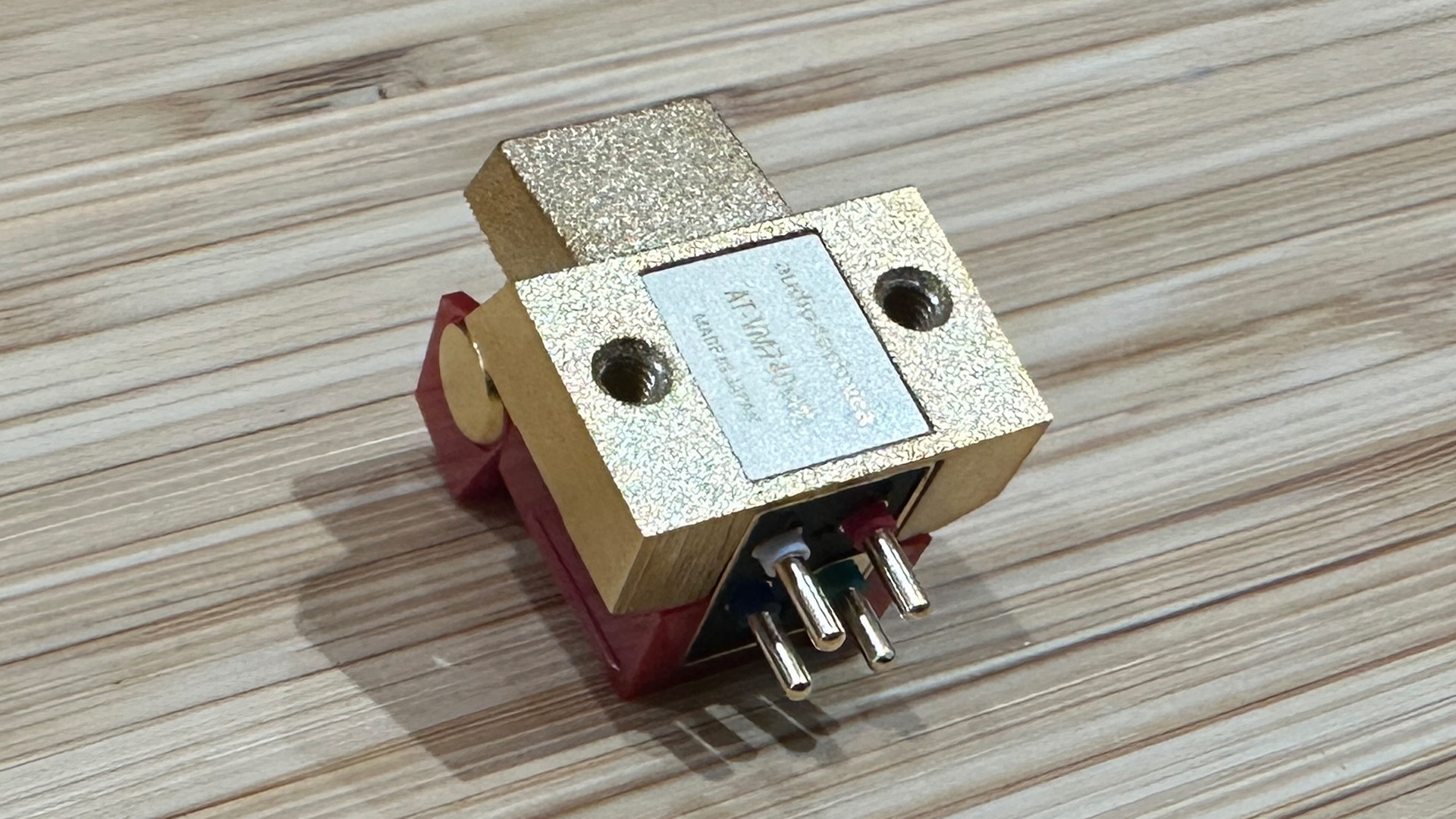 Audio-Technica AT-VM740xML moving magnet cartridge on wooden surface showing connecting pins