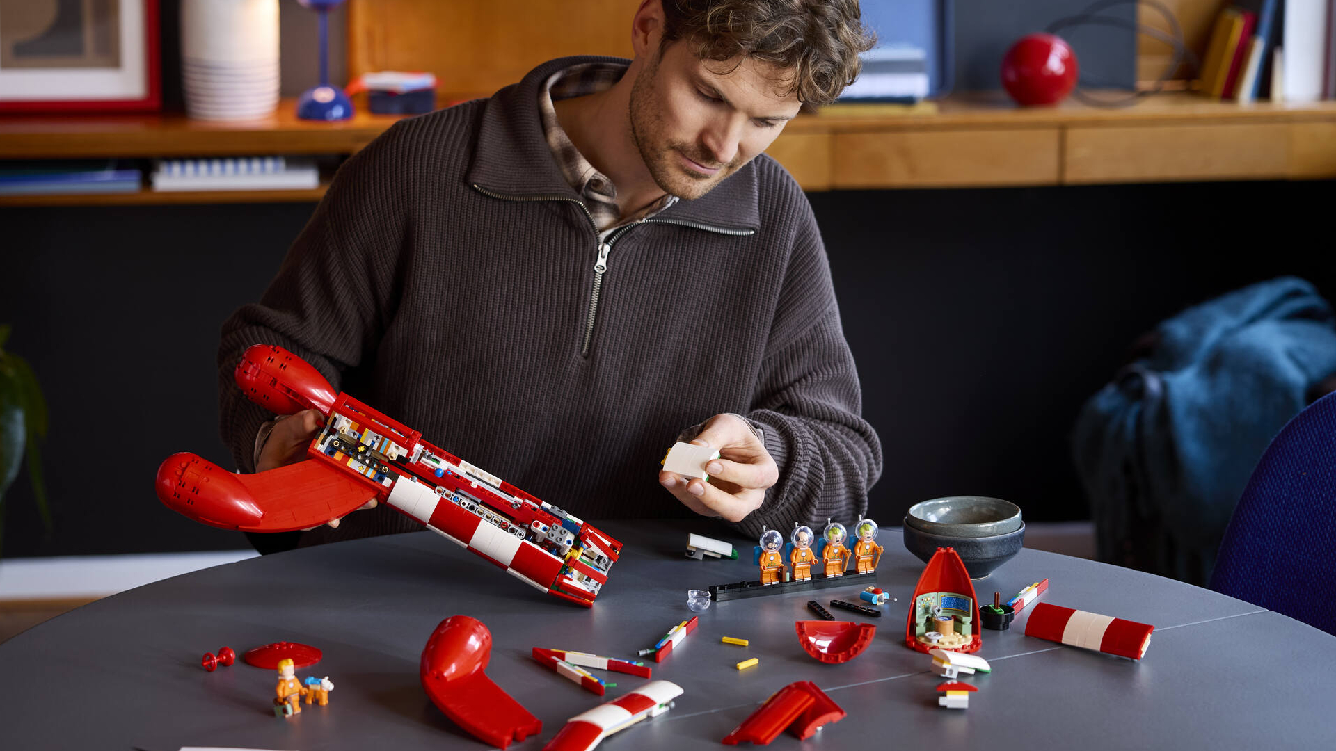 A man constructs the Tintin Moon Rocket in a home environment