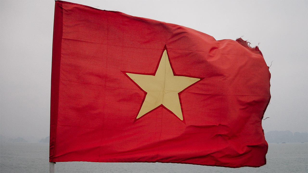 Flying flag of Vietnam. The flag is red with a single yellow star in the middle