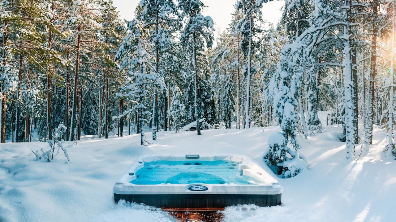 Hot tub in snow surrounded by trees