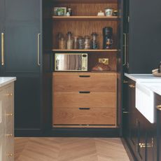 A pantry in a kitchen with a microwave and coffee machine inside