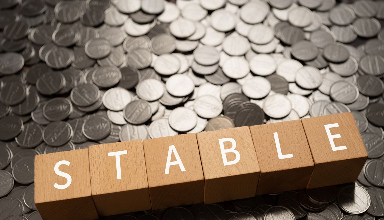 Wooden blocks with &quot;stable&quot; text sitting on coins.