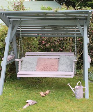 Swingseat painted in pink and grey accessorized with outdoor cushions