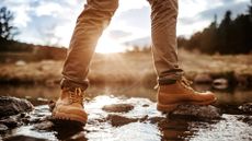 A person wearing waterproof hiking boots walking through some water