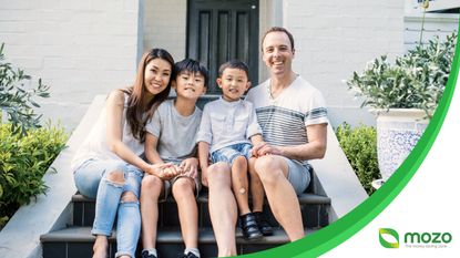 A family of four sit on a doorstep outside a home