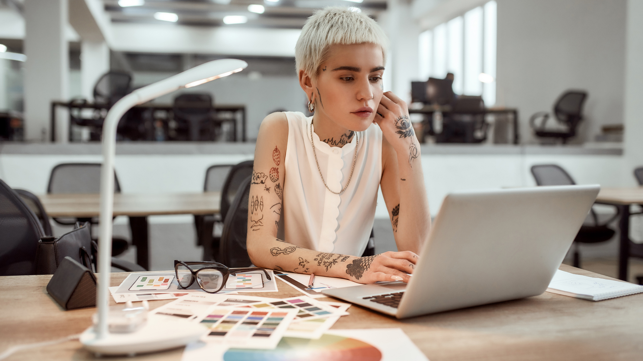 Young person working at a laptop on a desk in an office