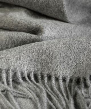 Close up of a fringed grey blanket