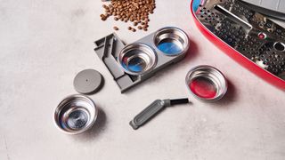 a red smeg espresso machine with burr grinder is photographed against a blue background