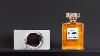 Sigma BF silver camera body and a bottle of Chanel No. 5 perfume sit side by side against a dark background