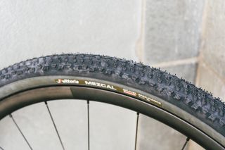 A black gravel tyre against a stone wall