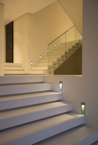 A modern concrete staircase lit up with floor lighting