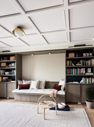 A living room with a niche between the books, with a fitted daybed in between