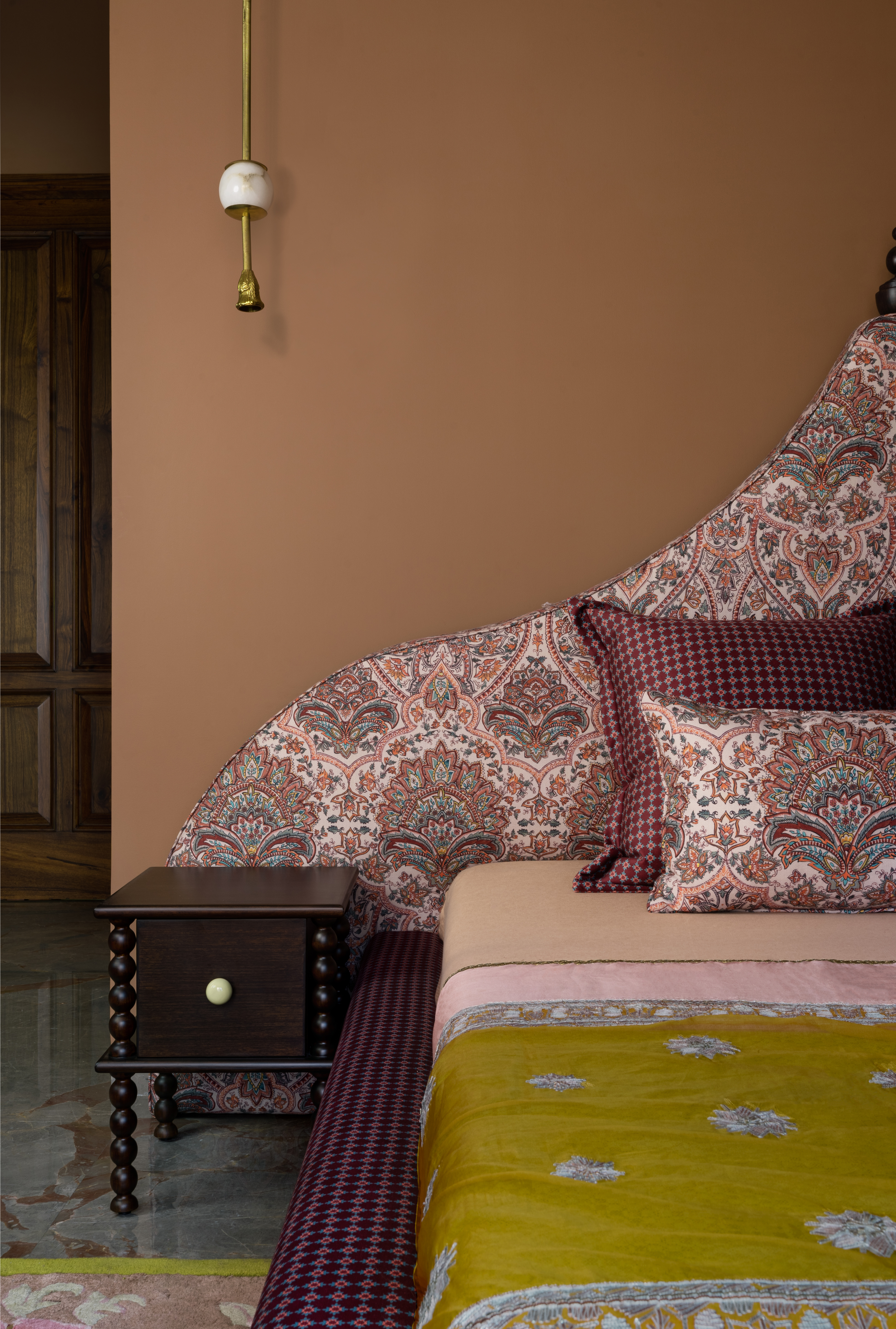 A sunken bed with a frame, headboard, cushions and top sheet in different complementary patterns