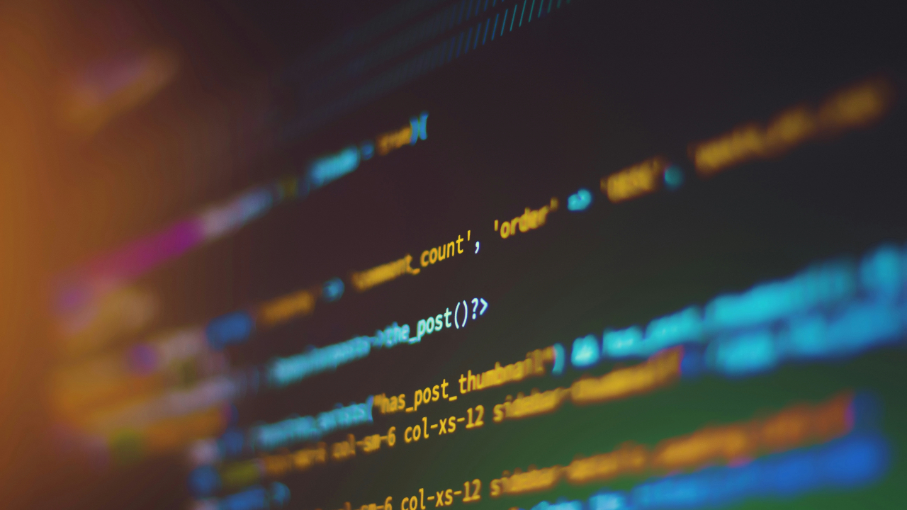 Lines of computer code in various colors are seen on a dark computer screen