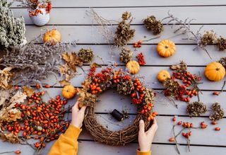 Autumn wreath making with berries, moss, and pumpkins.