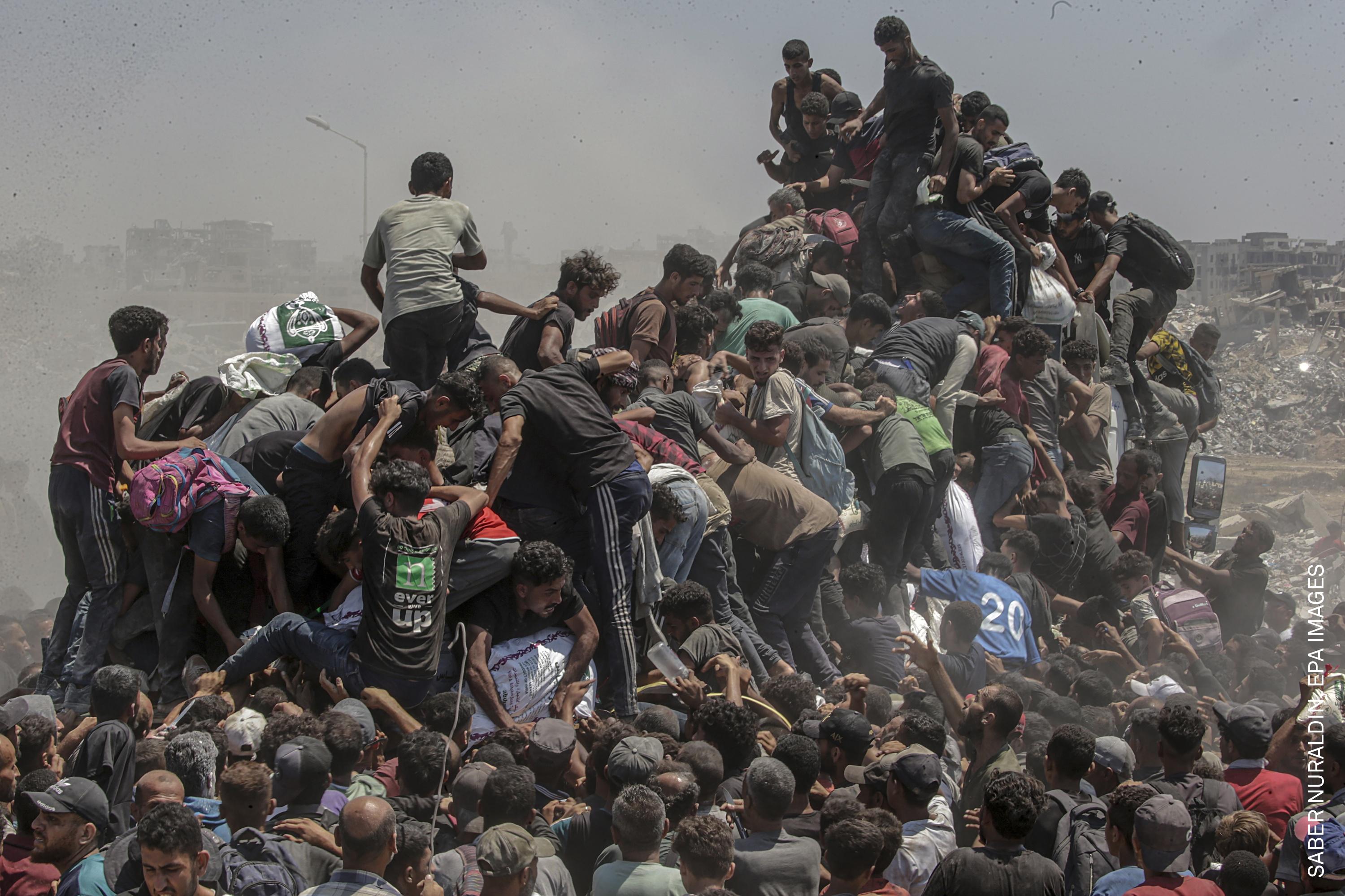 Palestinians climb onto an aid truck as it enters the Gaza Strip via the Zikim Crossing in an attempt to get flour, during what the Israeli military called a &amp;ldquo;tactical suspension&amp;rdquo; in operations