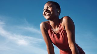 a woman in workout wear outside looking happy