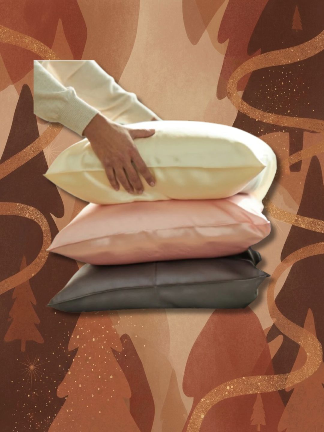 Stack of three silk pillows (grey, pink and cream) with hands reaching in to top one on brown graphic background with abstract Christmas trees and glitter