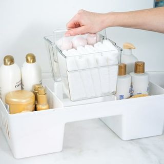 The Home Edit Xl Cleaning Caddy with a removable clear plastic section being lifted by a woman's hand