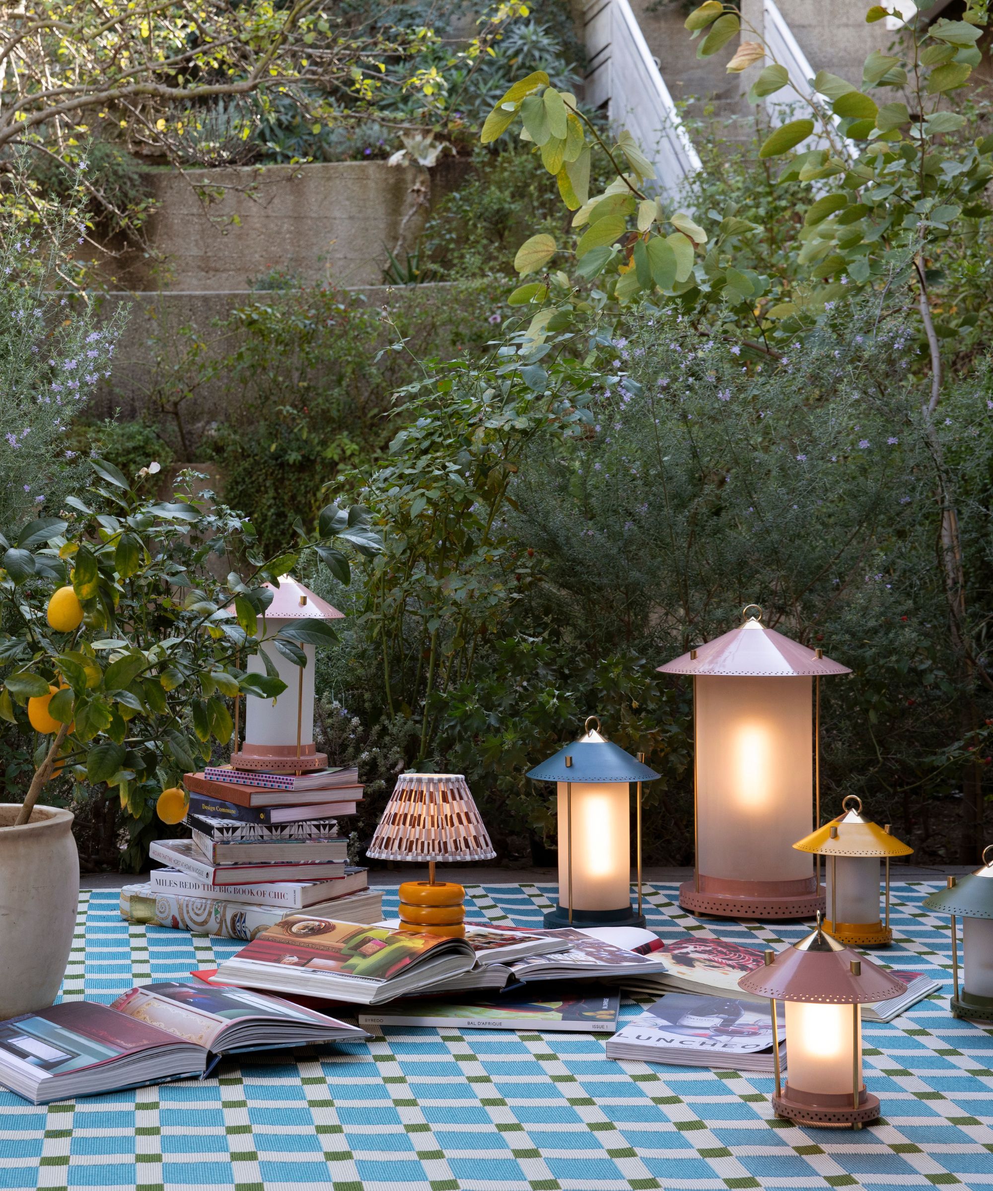 outdoor picnic rug styled with an orange tree and a series of different portable lantern style lamps