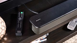 the sony ht-s100f or sony ht-sf150 in uk, a black soundbar with buttons on the top, a remote, photographed with a panasonic TV