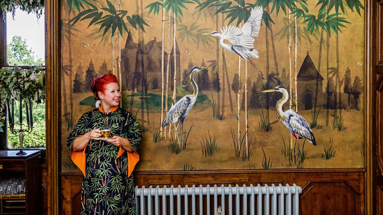 Angel Strawbridge standing in front of a wall mural showing herons and bamboo 