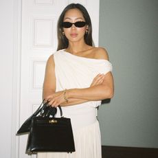 Aimee Song wearing a white dress and holding a black leather bag