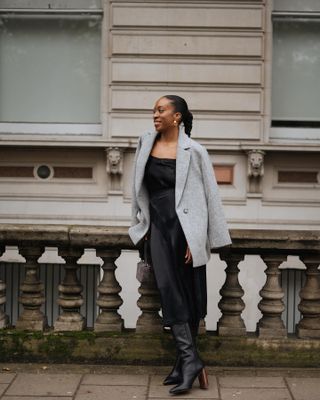 Chrissy Rutherford in a grey blazer, black slip dress, and boots.