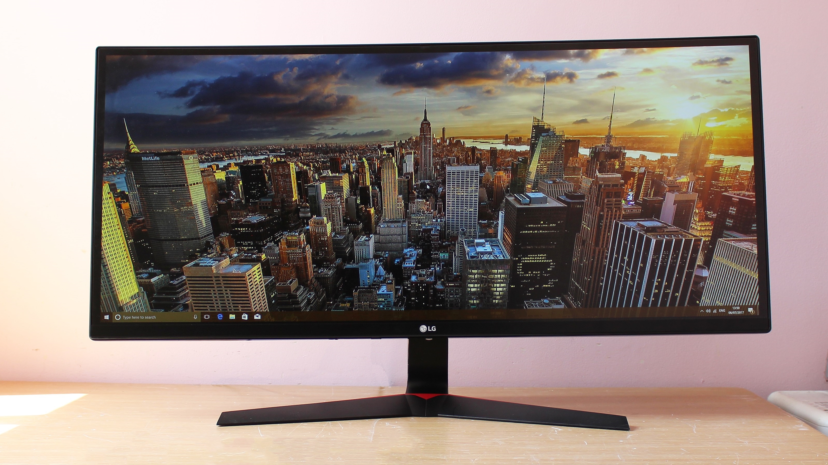 LG 34UC79G-B on a wood desk in front of a pink wall