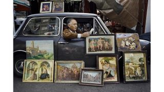 00472_20, Rome, Italy, 1984,ITALY-10041NF. A man displays paintings while he reads in his car.