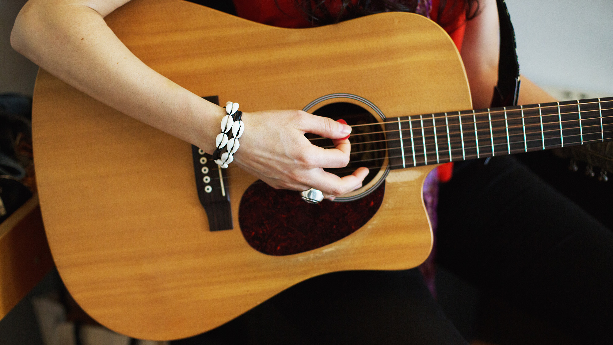 Young woman playing acoustic guitar at a recording studio