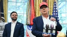 President Donald Trump shows off a picture of him and Russia's Vladimir Putin in Alaska