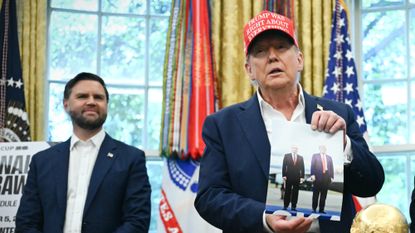 President Donald Trump shows off a picture of him and Russia's Vladimir Putin in Alaska