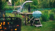An example of charcoal vs gas grills, a blue Weber kettle grill next to a Weber travel grill in a garden