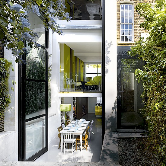Garden terrace with glass extension, green and black walls and green chairs