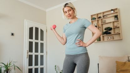 Woman exercising with one light dumbbell in a living room