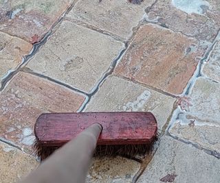 cleaning a patio with soapy water and a broom
