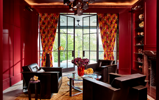 A red living room with black sofas and printed red curtains