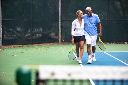 A senior black couple together on the tennis court.