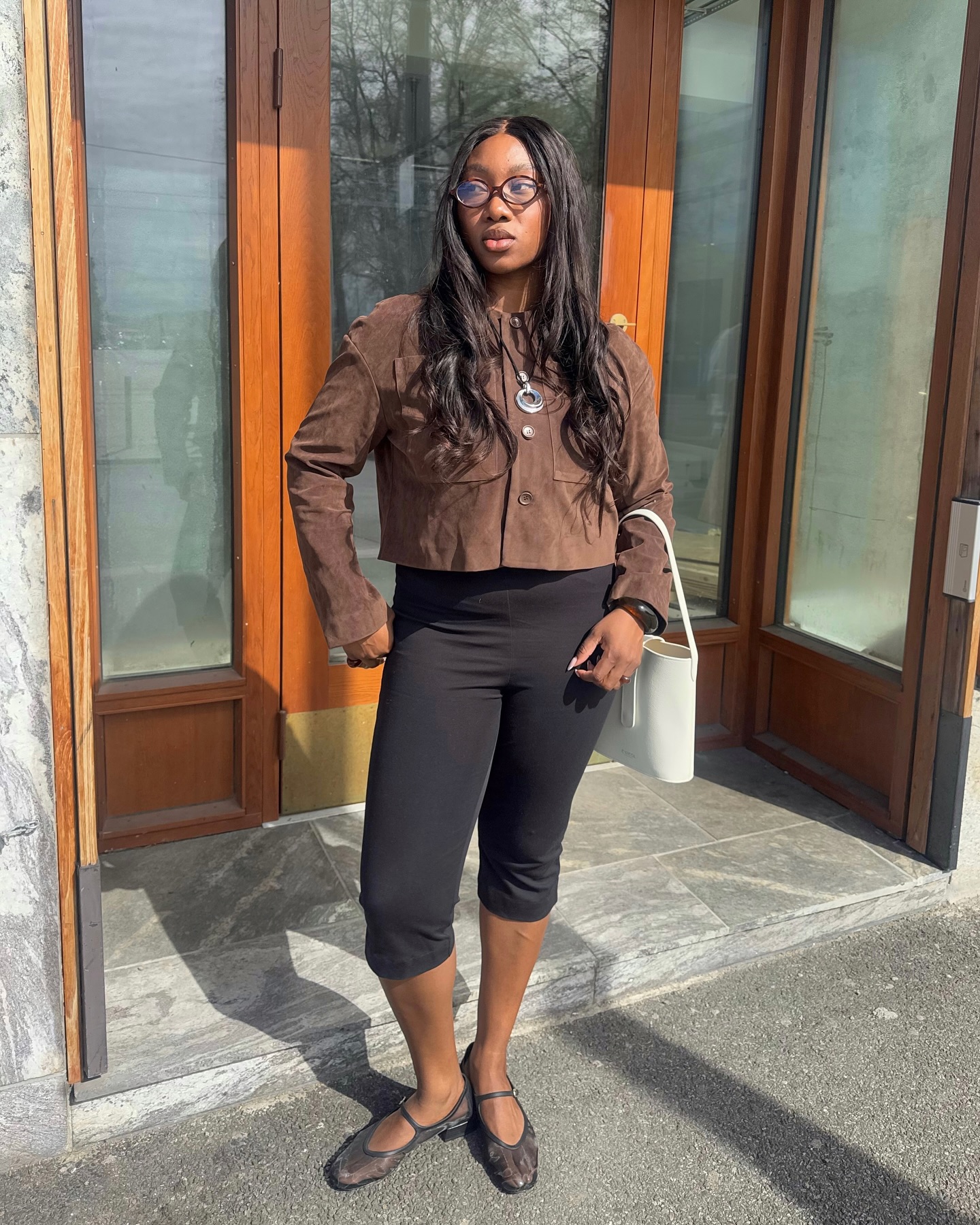 Nnenna Echem wears a suede brown jacket, black capri pants and mesh flat ballerina shoes, plus white handbag.