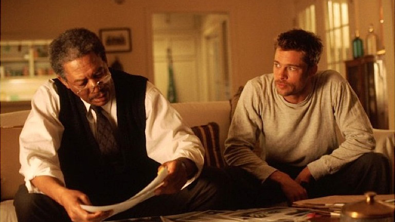 A still from the movie Seven in which Brad Pitt and Morgan Freeman's characters are sat next to each other on a settee.