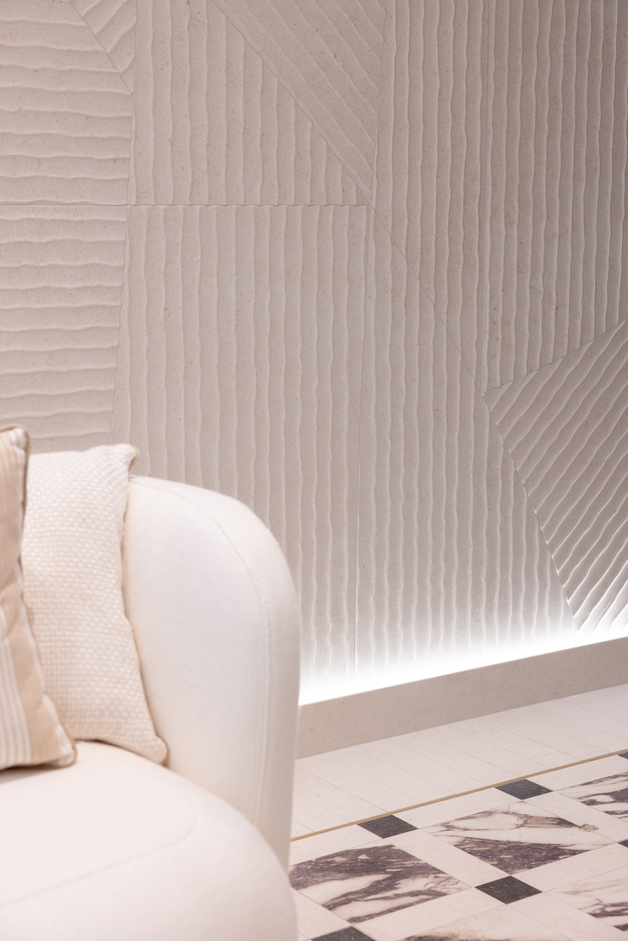 a textured wall lit from the floor with a mosaic marble-effect slab floor