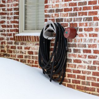 A hanging garden hose in a snow-covered garden