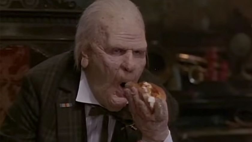 Dan Aykroyd with heavy makeup, looking like a very old man, eating a hot dog in Nothing But Trouble